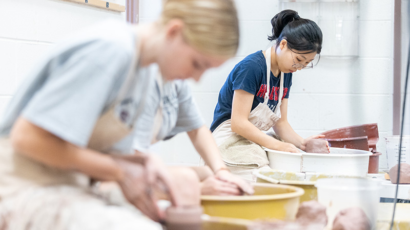 students in ceramics class at the potter's wheel