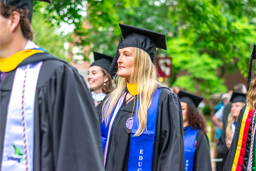 Photo of student smiling while walking in graduation procession
