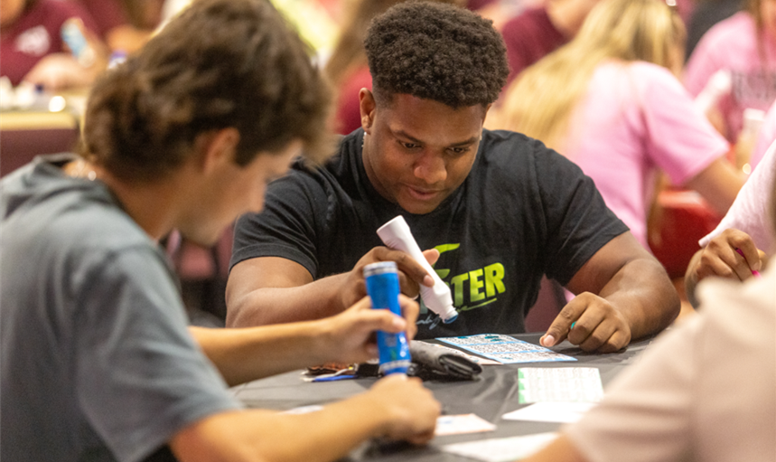 student playing bingo at a table of other students
