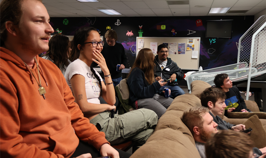 Students gathered about TV in the gameroom playing games on their phones