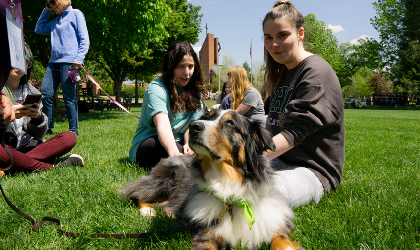 two students playing with a therapy dog