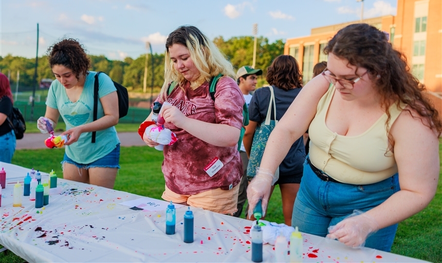 three students tie dying tshirts outside