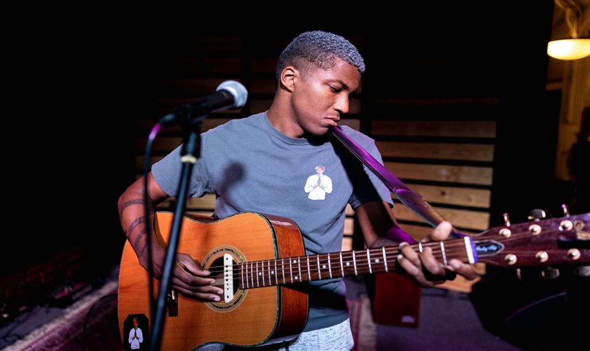 Dylan Dent singing on stage with a guitar 