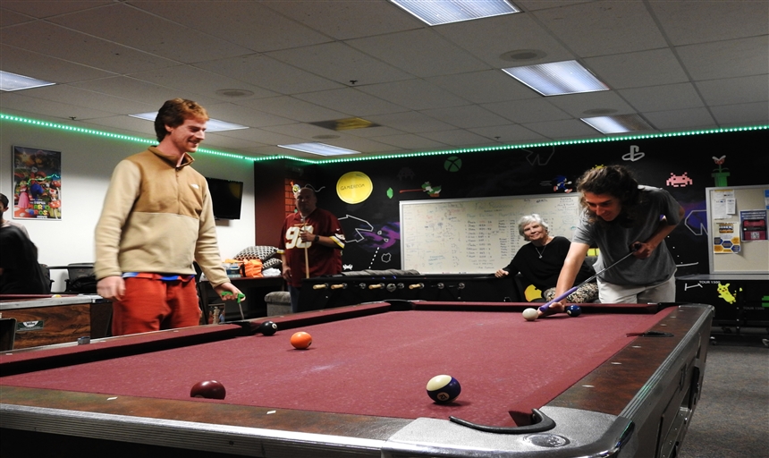 two students playing pool in the game room