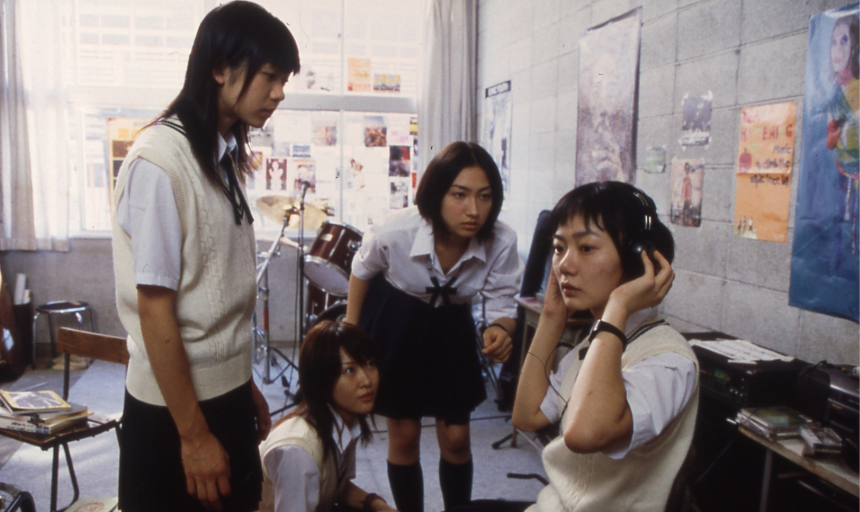Four girls gathered in a circle in a music room