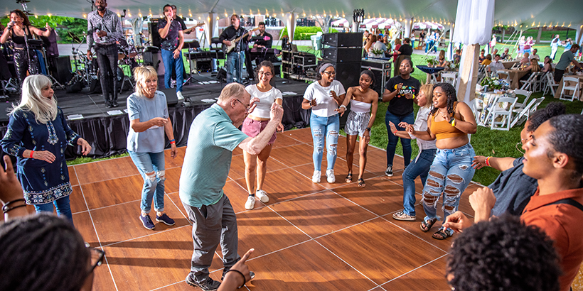 Man is in the middle of a circle of people on the dance floor