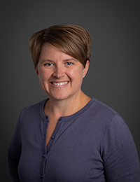 Headshot of a woman with short brown hair in a navy blue shirt