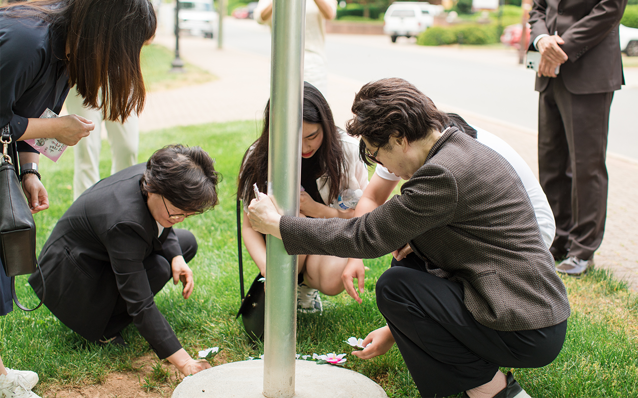 Four people place flowers around historical marker