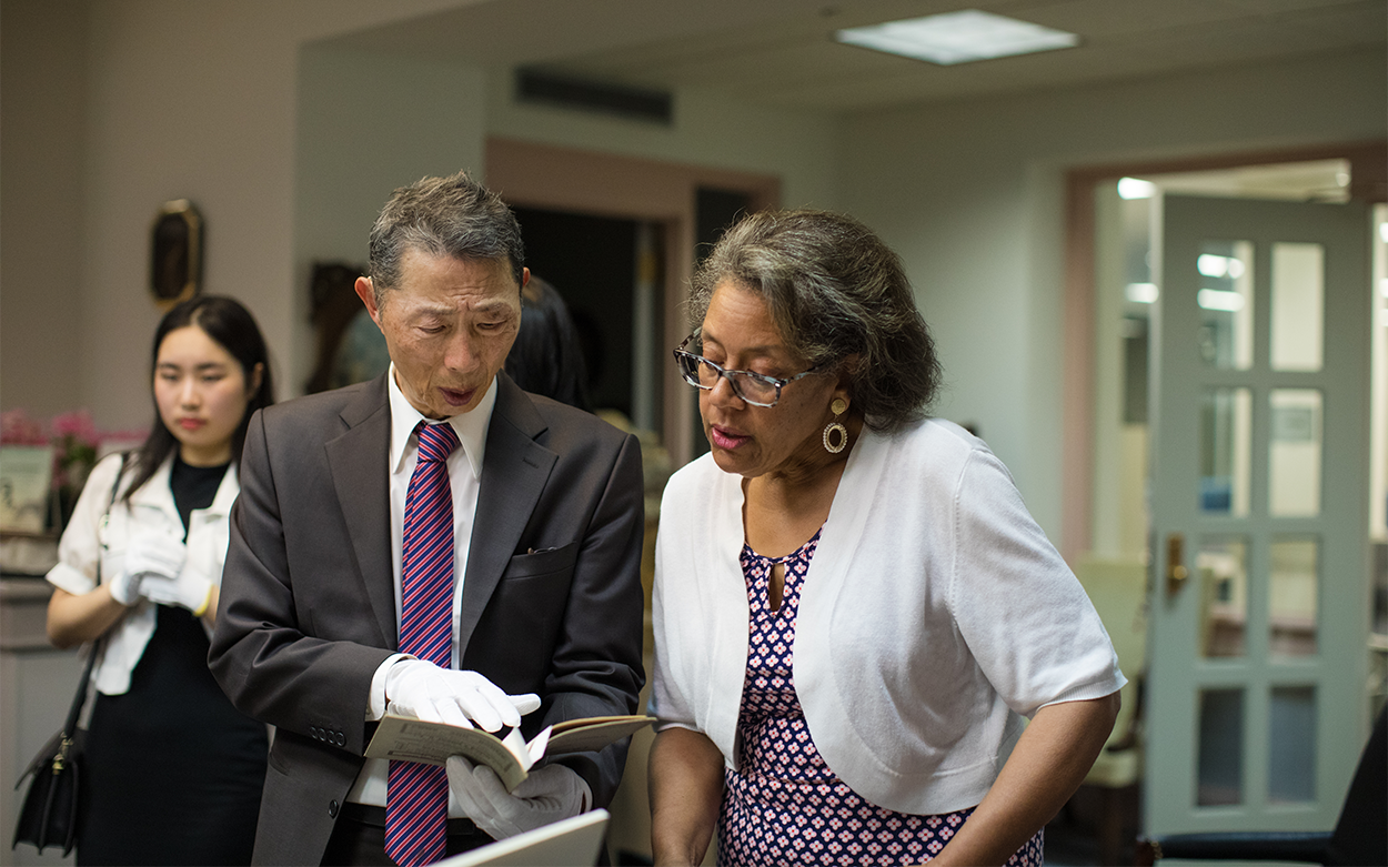 three people view historic materials while wearing gloves