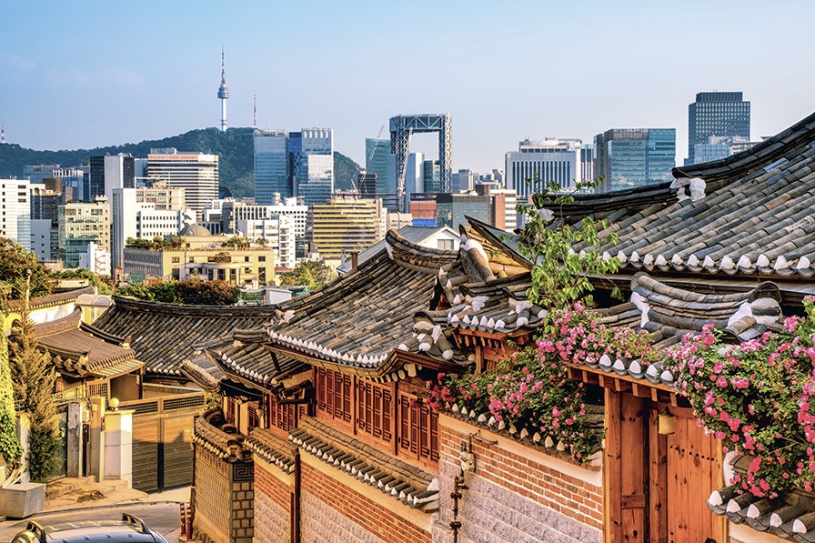 A view of a Korean cityscape where a mix of traditional homes and modern skyscrapers can be seen