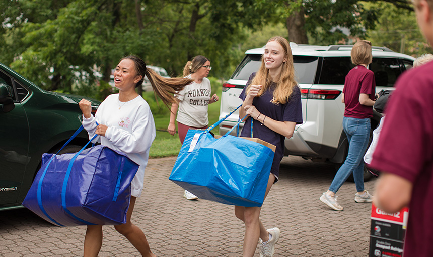 Students smile while carrying bags