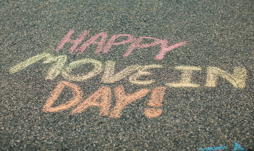 A chalk message written on the sidewalk reads: Happy Move In Day!