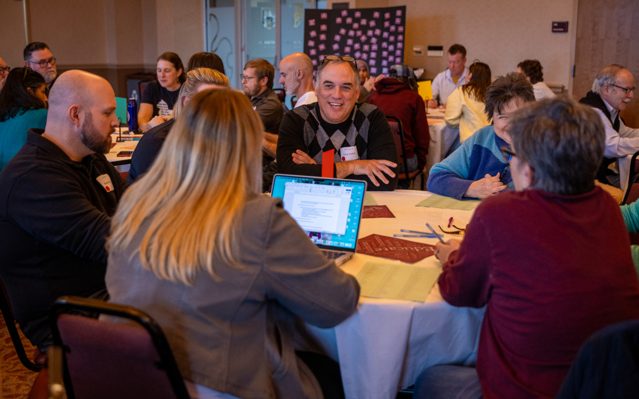Faculty and staff members sit around a table in the Wortmann Ballroom.