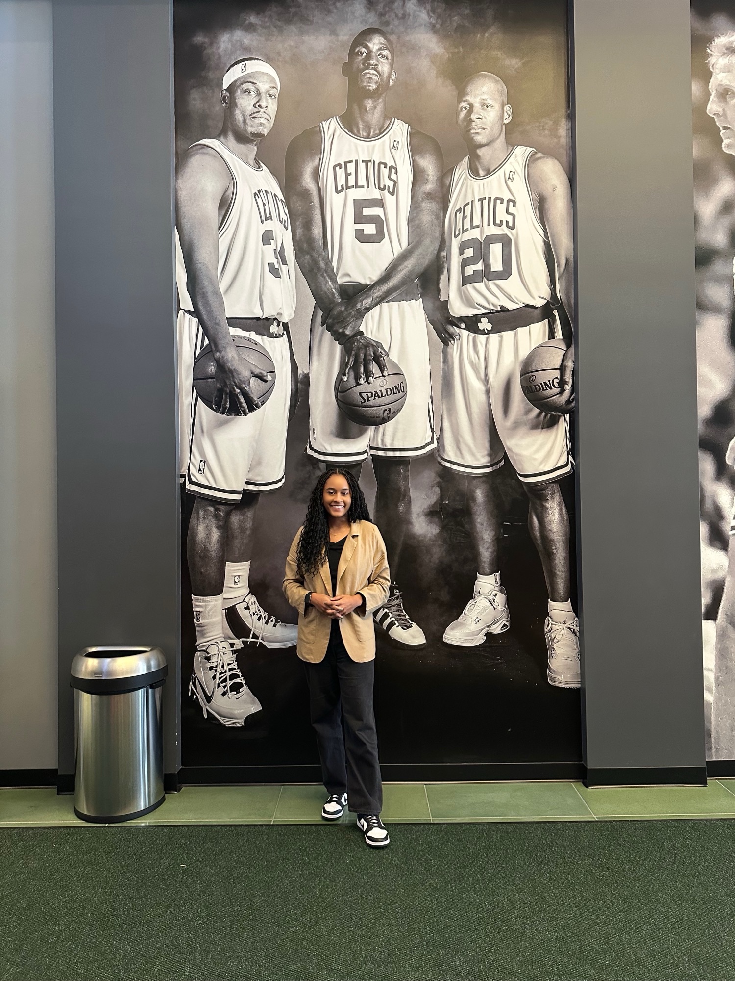 Woman stands in front of a large wall graphic that shows three Celtics players