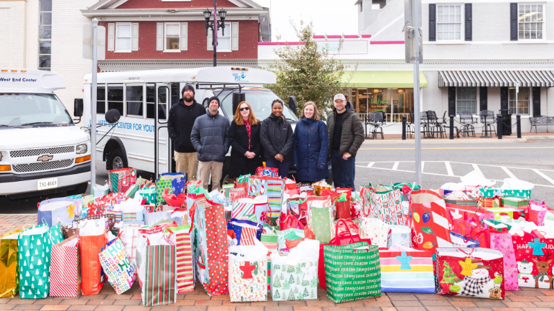 Roanoke College and West End Center representatives smiling while surrounded by holiday gift bags during the annual donation pickup
