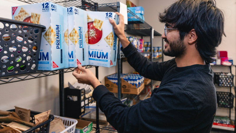 A student stocking shelves with boxes of crackers