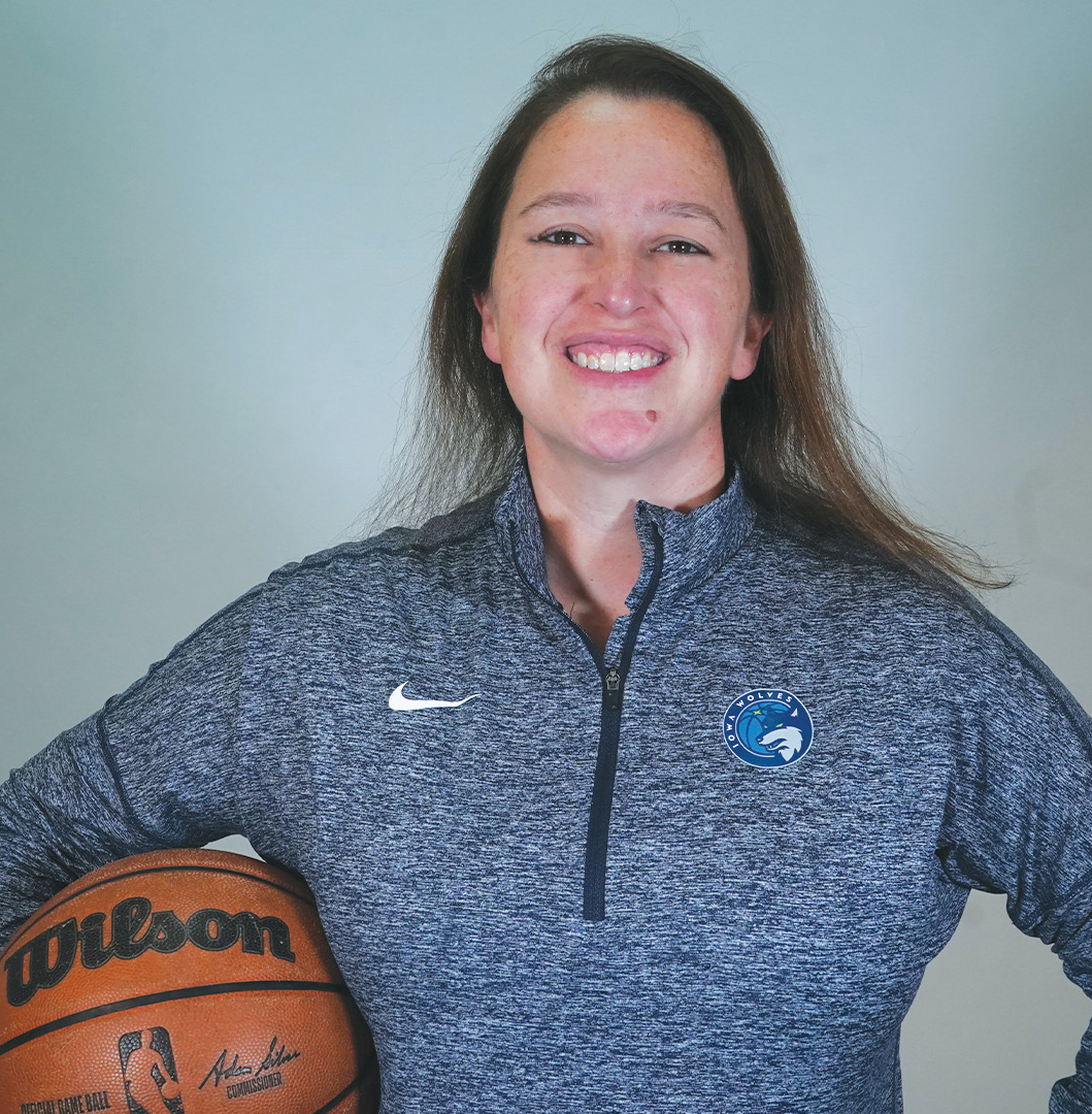 Smiling woman holding a basketball under one arm.