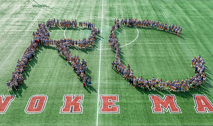 Students gathered on an athletic field to form the letters RC
