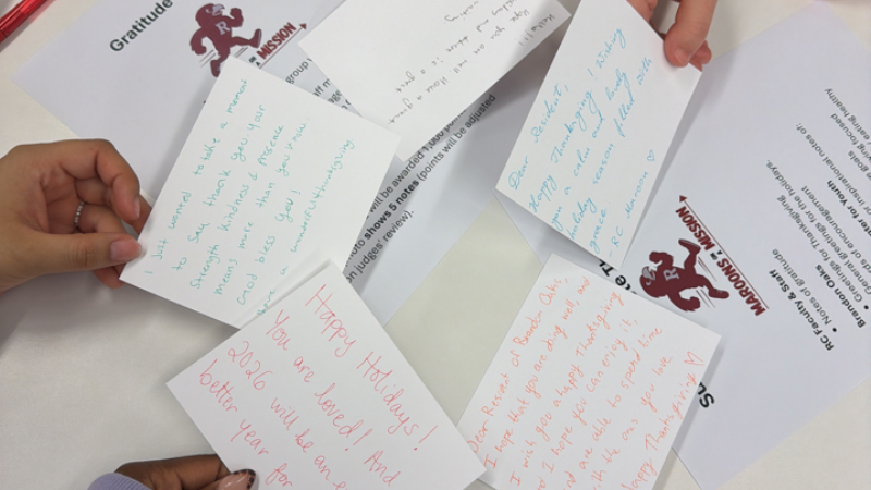 Closeup of hands holding up four handwritten cards