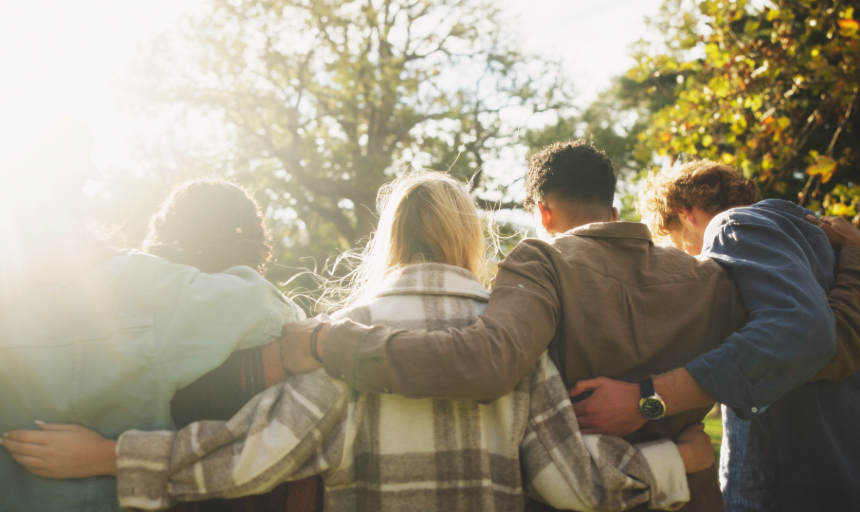 A group of people stand side by side with their arms around each other's shoulders