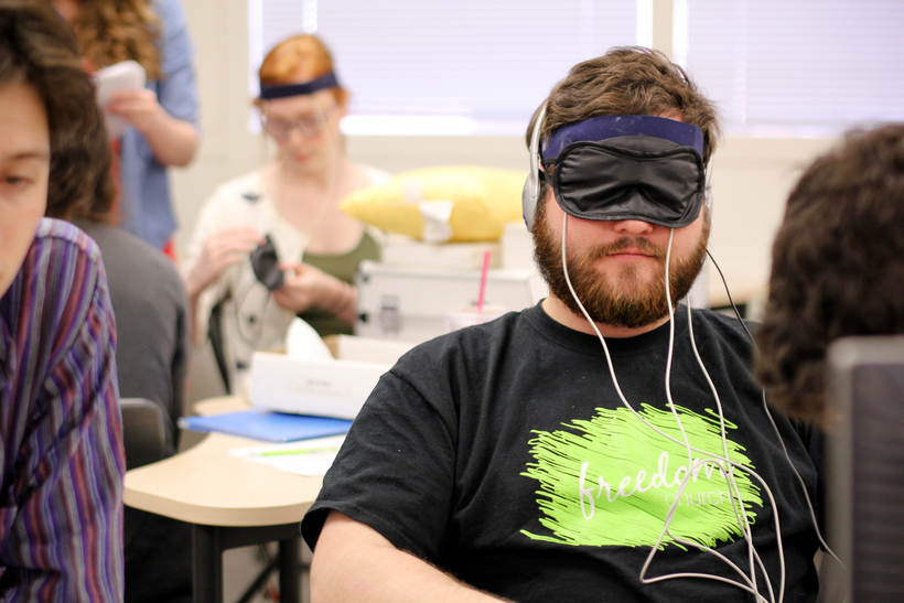 A student sits while hooked up to wires for a experiment