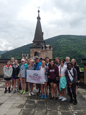 Students at a large building in Slovakia holding a Roanoke College banner
